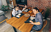 From above of mother captures a photo of her children enjoying breakfast at home, featuring a warm and inviting dining setting
