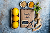 Fresh lemons, ginger, and spices displayed around a notepad with Healthy eating written on it