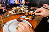 People sharing a variety of gourmet dishes and glasses of red wine at a cozy dining table setting
