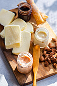 Eine Gourmet-Käseauswahl auf einem Holzbrett, gepaart mit Honig, Nüssen und köstlichen Brotaufstrichen, perfekt für elegante Snacks oder Gäste