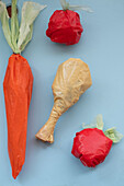 Konzeptuelles Kunstwerk, das aus Plastiktüten geformte Lebensmittel auf blauem Hintergrund zeigt.