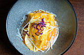 Von oben: Verlockender Teller mit Käse- und Walnusstortellini, garniert mit geriebenem Käse und lila Mikrogrün, serviert in einer modernen grauen Schale.