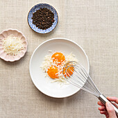 Draufsicht auf die Zutaten für Spaghetti Carbonara mit Eiern, Käse und Pfeffer auf neutralem Hintergrund.