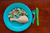 From above children's plate displays an assortment of plastic bags cut and arranged to resemble food, illustrating concerns about plastic waste and its impact on future generations.