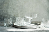An artistic arrangement of empty textured glasses on a round stone tray, casting soft shadows under ambient lighting