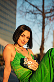 A stylish woman poses confidently in a vibrant green dress against Madrid's 4 Towers area, showcasing urban chic.