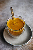 A warm, golden turmeric latte sits in a ceramic cup