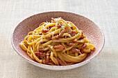Eine Schüssel mit frisch zubereiteten Spaghetti Carbonara mit knusprigen Pancetta-Stückchen und geriebenem Käse darauf.