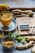 Ein köstlicher goldener Kurkuma-Tee, Zutaten und ein Konzept für gesunde Ernährung auf einem rustikalen Tisch