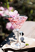 Pink gin cocktail with flower and ice cubes