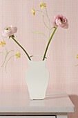 DIY vase with two pink ranunculus on wooden table