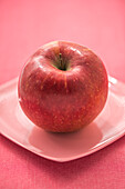 Ein roter Apfel auf Keramikteller