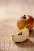Ganzer Apfel und Apfelspalte auf Holztisch