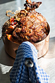 Leg of lamb in a copper pot with vegetables