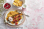 Heart-shaped waffles with cream, chocolate sauce and raspberries