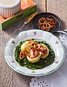 Potato dumplings filled with smoked pork on spinach