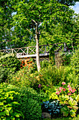 Üppiger Garten mit Brücke und blühenden Pflanzen im Sommer