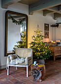 Living area decorated for Christmas with illuminated Christmas tree and mirror