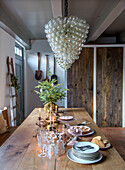 Rustic dining table with candles and Christmas decorations under a large glass lamp