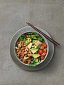 Quinoa bowl with tofu, avocado, cashew nuts and tomatoes