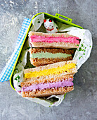 Colourful sandwiches in a lunch box with vegetable skewer