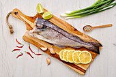 Raw haddock on a wooden board with citrus fruits and garlic