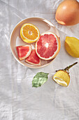 Various citrus fruits in a bowl and on a white linen tablecloth