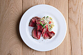 Roast beef with Olivier salad on a white plate