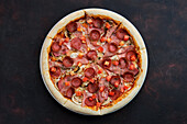 Pizza with ham, bacon, sausage, tomato and mushrooms