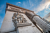Der Arc de Triomphe mit seinen detaillierten Skulpturen vor einem düsteren Himmel.
