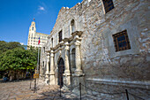 Der historische Alamo auf der Alamo Plaza mit dem dahinter liegenden Emily Morgan Hotel in San Antonio, Texas. Das Emily Morgan Hotel wurde 1924 als Medical Arts Building erbaut.