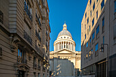 The grand dome of Le Panthéon stands out against a clear sky as seen from a Parisian street.