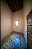 Spärliches Studentenzimmer mit traditionellen Kacheln und kleinem Fenster in der Cherratine Madrasa. Fez, Marokko.