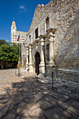 Der historische Alamo auf der Alamo Plaza mit dem dahinter liegenden Emily Morgan Hotel in San Antonio, Texas. Das Emily Morgan Hotel wurde 1924 als Medical Arts Building erbaut.