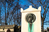 The grave of painter Louis David featuring a sculpted medallion in a tranquil setting.