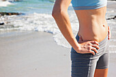 Woman on Beach in Sportswear with Hands on Hips, Mid Section