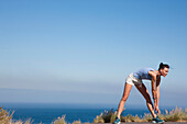 Woman Stretching against Ocean and Blue Sky