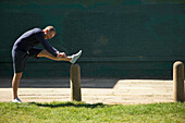 Mature Man Stretching Leg in the Park