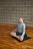 Älterer Mann übt Yoga, leichte Stellung