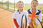 Zwei Jungen halten Tennisschläger und lächeln