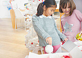 Zwei junge Mädchen, die Weihnachtskugeln aus Schachteln nehmen