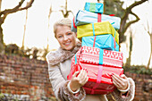 Junge Frau hält Stapel von Weihnachtsgeschenken im Freien