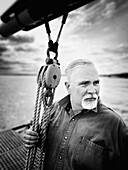 Head and shoulders portrait of mid-adult man looking away on sailboat