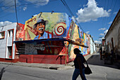 Kuba,santiago,eine Frau geht vor einem großen bunten Gemälde an einer Hauswand spazieren