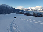 Österreich,Tirol,ein Mann mit einem gelben Rucksack wandert im Neuschnee vor den Stubaier Alpen