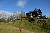 Österreich,Steiermark,ENNSTAL Alpen, ein einsamer Mann mit rotem Rucksack geht zur Mödlinger Hütte oberhalb der kleinen Stadt Admont, ein hohes Holzkreuz steht vor dem Hütteneingang
