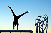 USA. Florida. Miami. Miami Beach. South Beach. Ocean Drive. Man practicing gymnastics at dusk.