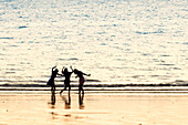 France. Normandy. Department of Manche. Granville region. Teenage girls dancing on the beach at high tide.