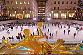 USA. New York City. Manhattan. Rockefeller Center im Winter. Statue Prometheus, von Paul Howard Manship (1885 - 1966). Eisbahn. Touristen beim Schlittschuhlaufen.