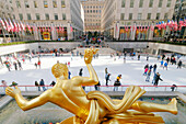 USA. New York City. Manhattan. Rockefeller Center im Winter. Statue Prometheus, von Paul Howard Manship (1885 - 1966). Eisbahn. Touristen beim Schlittschuhlaufen.
